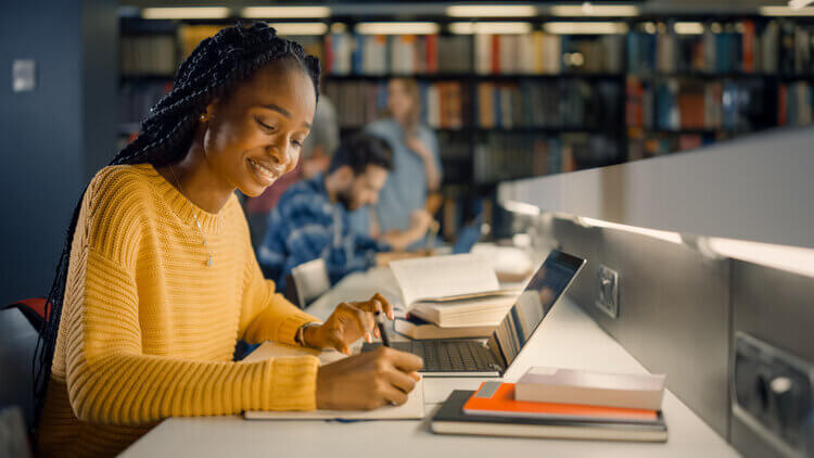 Student on laptop in library studying for social work program