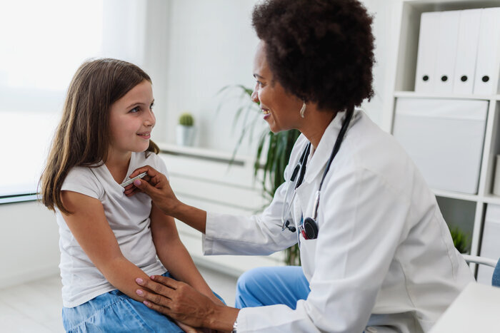 Pediatric nurse examining a child with a stethoscope 